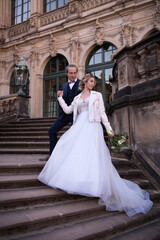 Full length portrait of a bride and groom enjoying romantic moments while standing on the stone steps of a beautiful castle. Wedding couple.