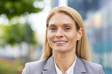 This image features a confident businesswoman smiling outdoors, capturing her natural light...