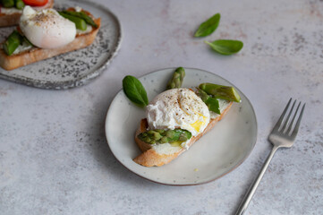 Toast bruschetta with grilled asparagus, poached egg and fresh cream cheese. Sourdough bread with vegetables and egg. Food photography. Healthy breakfast, brunch.