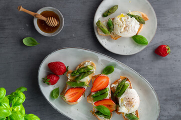 Toast bruschetta with grilled asparagus, poached egg, strawberry and fresh cream cheese. Sourdough bread with vegetables and egg. Food photography. Healthy breakfast, brunch. Summer food