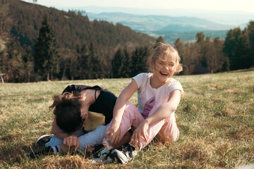 Two girls in nature in the mountains laugh merrily and have a great time together. Friendship and fun