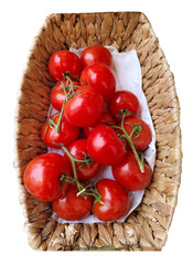 Top view of fresh red tomatoes in wicker basket isolated on white background. Spot focus.