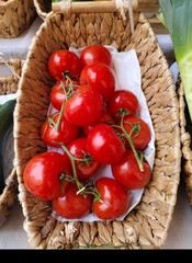 Top view of fresh red tomatoes in wicker basket isolated on white background. Spot focus.