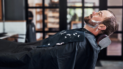 Man, customer and beard care in barbershop, wash and trim or neat facial line up for client in all...
