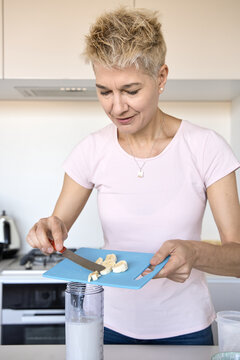 Woman added sliced banana into blender for smoothie