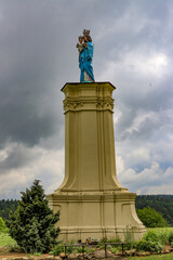 Figure of Mary in a blue robe on a large yellow pedestal