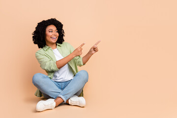 Full size photo of nice young lady direct fingers empty space wear shirt isolated on beige color background