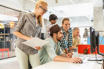 Diverse group of coworkers collaborating on a project using a computer in a modern office