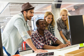 Diverse group of coworkers collaborating on a project using a computer in a modern office