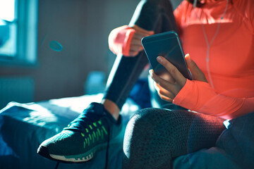Female athlete using smartphone while resting after workout
