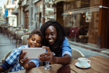 Black mother and son taking a selfie at a cafe