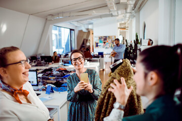Female designer taking picture of finished product with colleagues in office