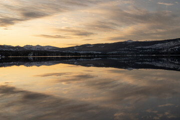 Dramatic sunset. View of the lake and mountains at twilight. The sky and landscape reflection in the water surface.