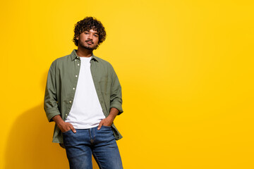 Photo of young handsome model hispanic guy empty space in khaki shirt and jeans posing exclusive brand isolated on yellow color background