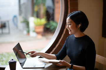 A woman is sitting at a table with a laptop and a notebook