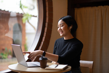 A woman is sitting at a table with a laptop and a cup of coffee