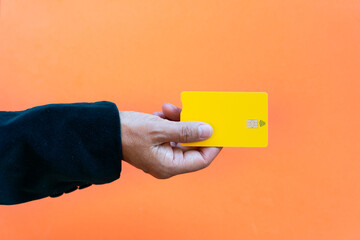 Concept purchasing with contact less chip card Chip debit card. close up of woman hand on orange background holding yellow card.