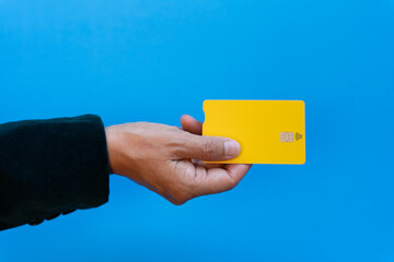 Concept contact less payment with debit card. Woman hand holding card with yellow color and blue background