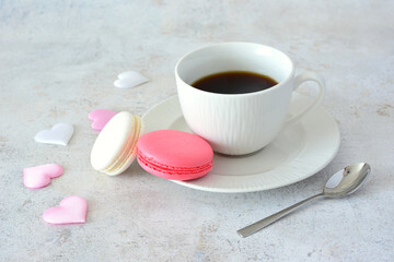 a cup of coffee with macaroons and pink and white silk hearts 