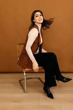 Stylish lady sitting on wicker chair and flicking hair