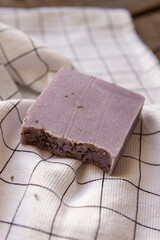 A piece of natural soap on white checkered towel. Lavender soap