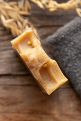A piece of natural household soap and towel on wooden background. Soft focus. Handmade soap
