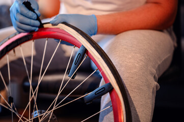 A mechanic wearing blue gloves repairing a bicycle tire indoors, focusing on the rim and tire...