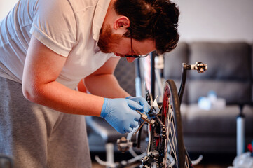 A mechanic wearing blue gloves repairing a bicycle chain indoors, focusing on the intricate work...