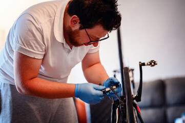A mechanic wearing blue gloves adjusting a bicycle chain with a specialized tool, focusing on...