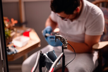 A man wearing gloves works on a bicycle in his home workshop, focusing on the bike's handlebar.