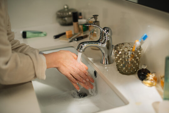 Anonymous woman washing hands in bathroom sink