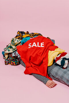 covered by a pile of clothes and a red shirt with the word sale
