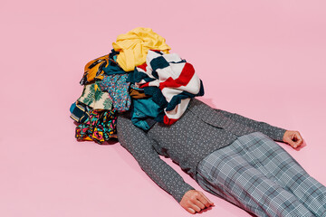 man is lying under a pile of clothes