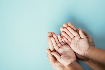 Studio shot, Close-up top view family hands stacked on an isolated background. Parents and kid hold...