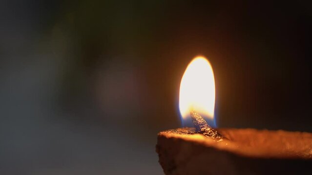 macro close up shot of flame from an oil covered cotton wick in an organic plant fiber diya clay lamp showing the celebrations on the festival of diwali in India
