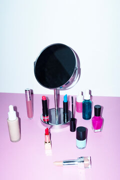 Pink table with mirror & make-up: lipsticks, nail polish, foundation