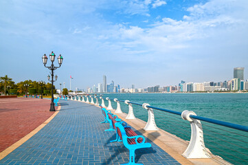Waterfront view of Abu Dhabi with sea, skyscrapers from Corniche embankment.