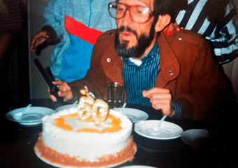 Man blowing out the candle on his birthday cake