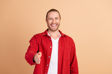 Photo of nice young man handshake you wear red shirt isolated on beige color background