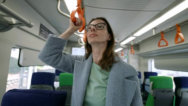 Among the comforts of public transport, a middle-aged woman in trendy glasses emphasizes her personality and sense of style.