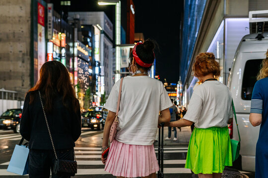 Young women waiting to cross a zebra crossing along a shopping street