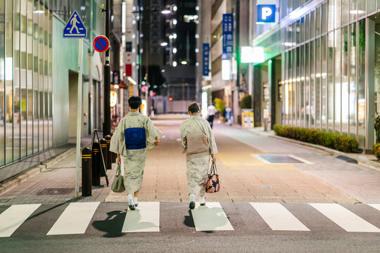 Anonymous young women wearing traditional kimono costumes at night