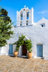 Typical Greek white church with flower pots in Artemonas village against blue sunny sky, Sifnos...