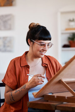 Art, creative and smile with woman in home for design, expression or inspiration on weekend. Drawing. pencil and wooden table with happy artist in apartment for break, hobby or sketch as illustrator