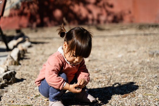 Toddler Playing with Pebbles Outside