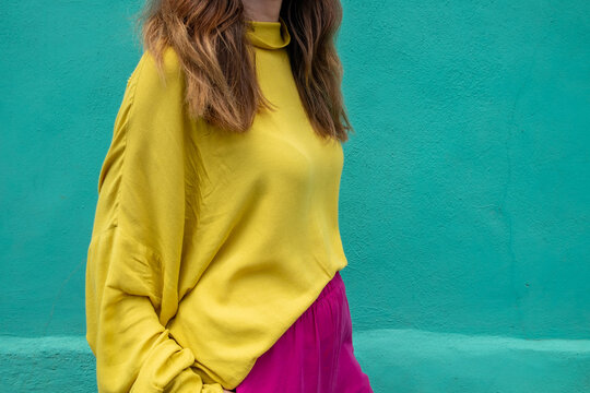 Anonymous female in front of a turquoise wall in colorful clothes