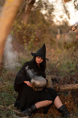 A witch dressed in black dress in the forest	