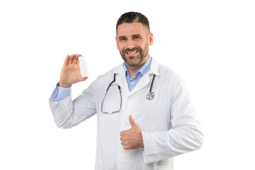 A man doctor with a stethoscope around neck smiles while holding a white medication bottle in one...