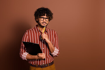 Photo of nice young man clipboard ponder wear striped shirt isolated on brown color background