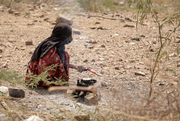A woman makes food for her displaced children in displacement camps in Taiz, Yemen